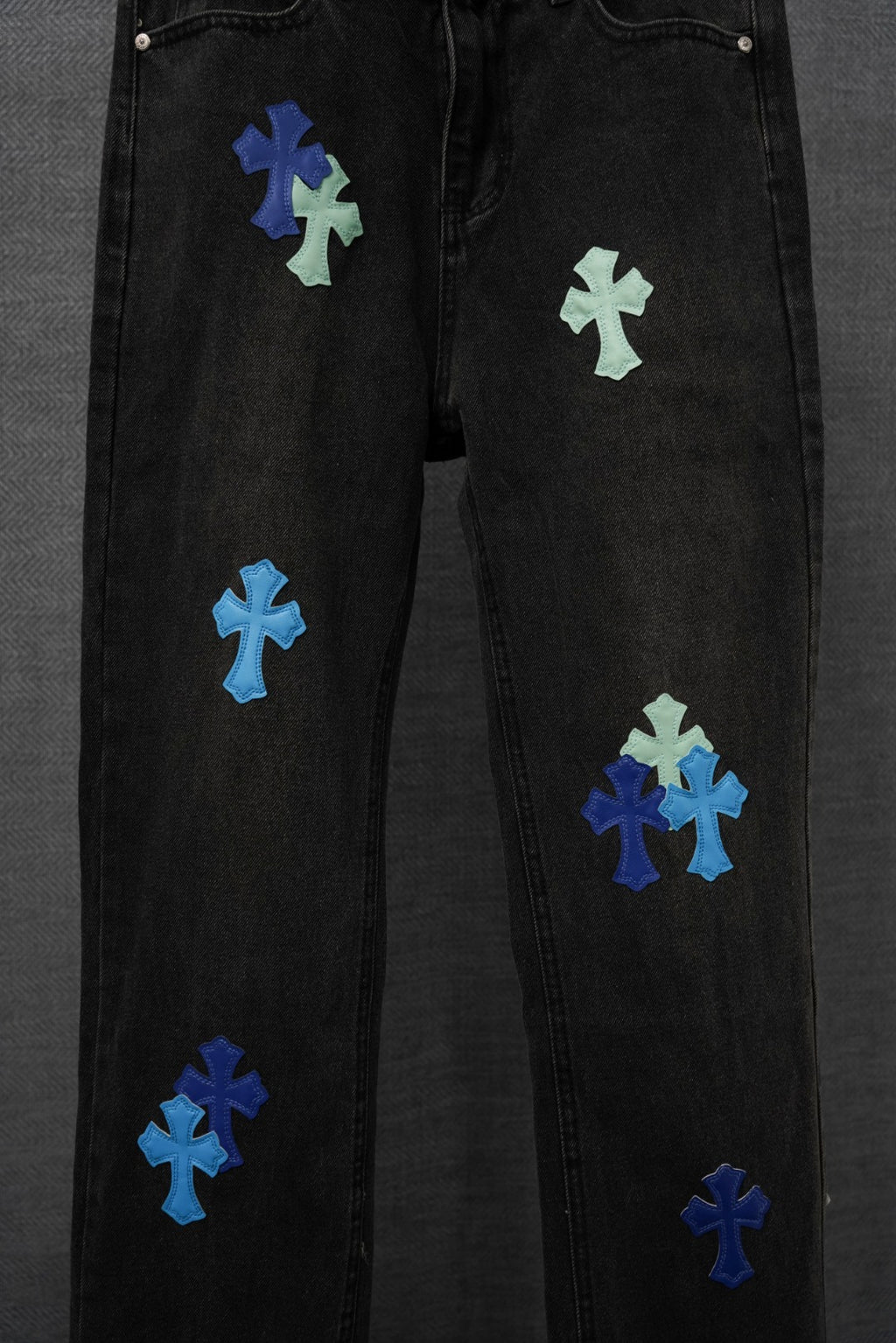 Black denim pants side view with multiple multicolor cross patches