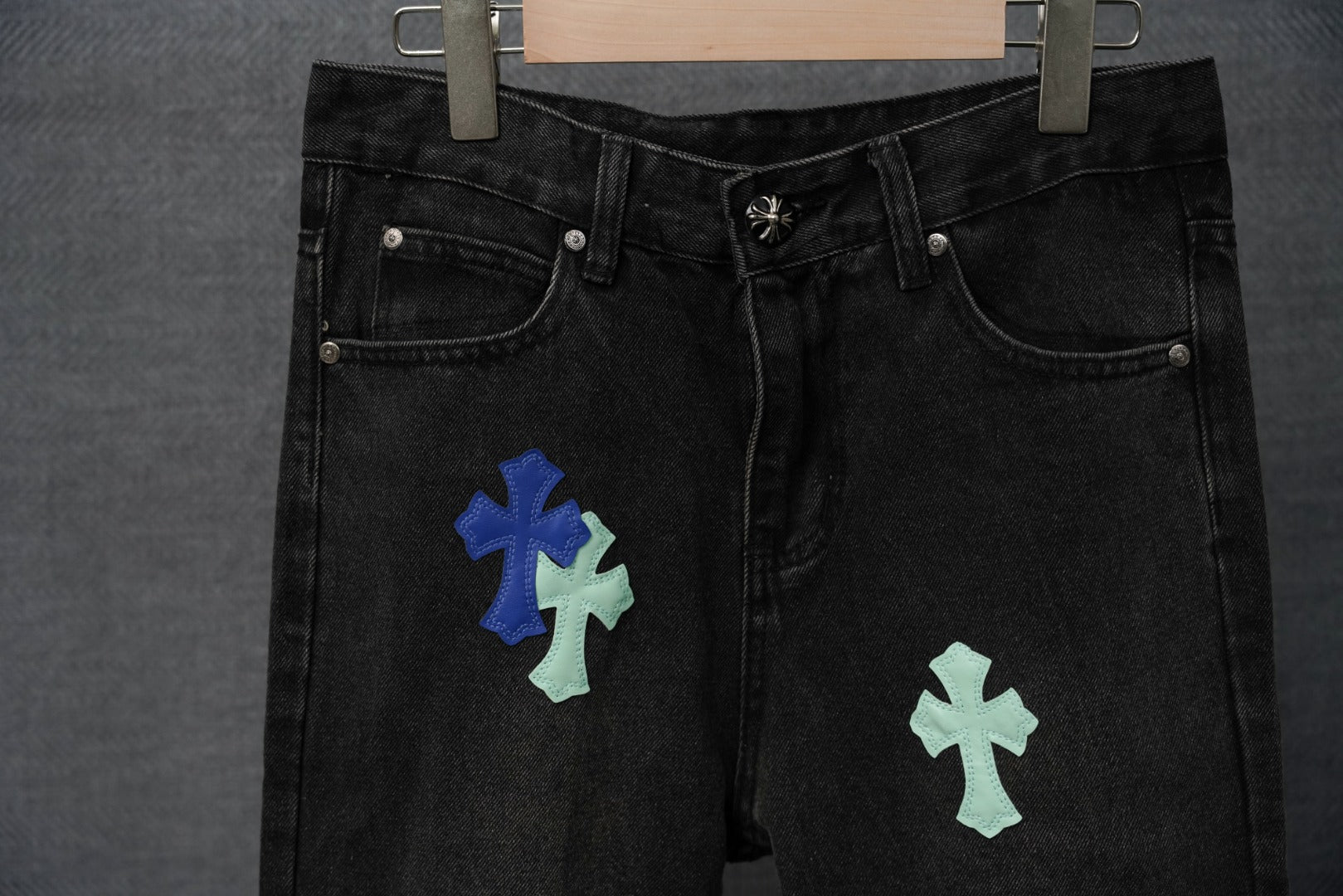 Black denim pants front view with multicolor cross patches and denim buttons