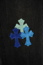Black denim pants close-up of mint and blue cross patches on fabric