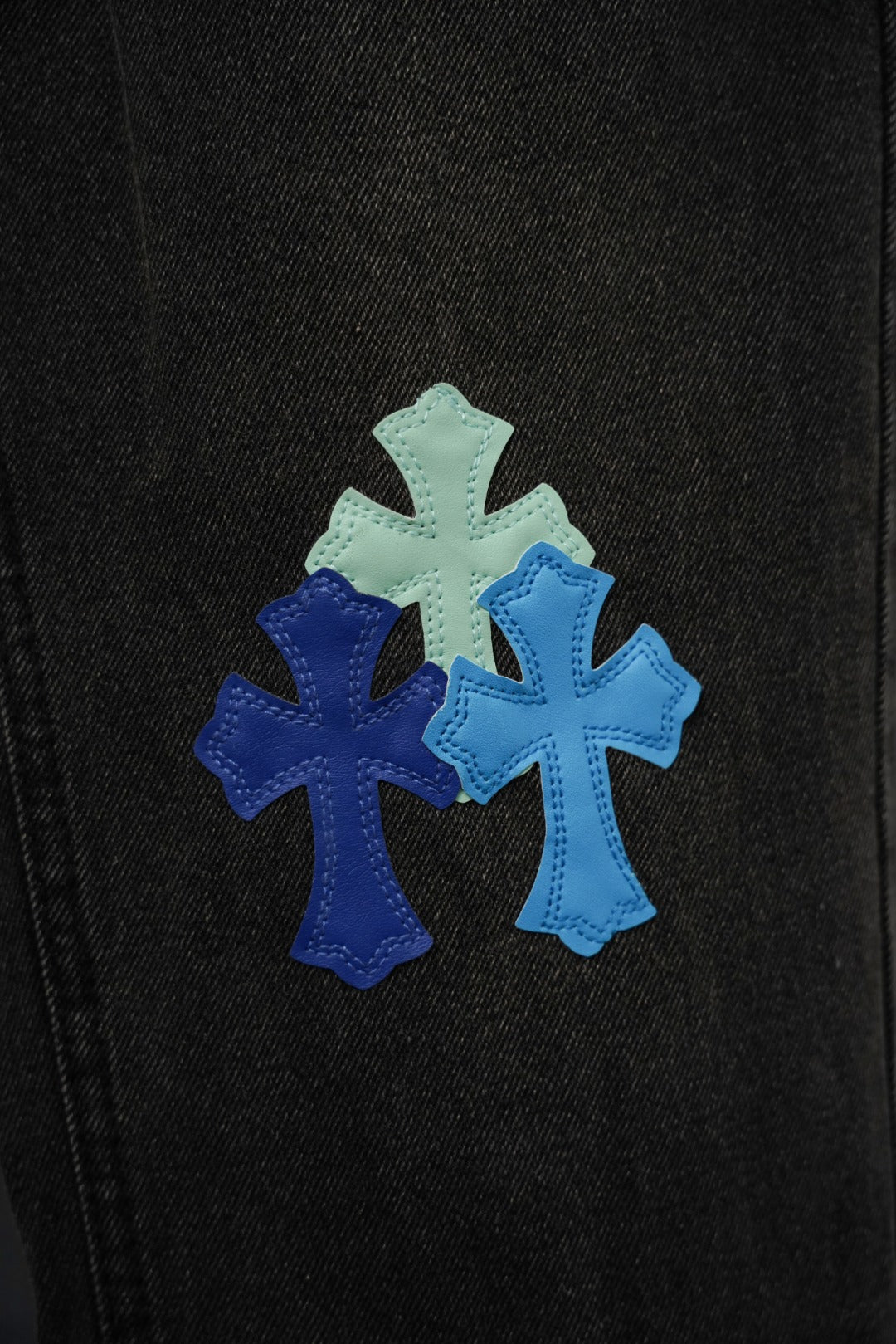 Black denim fabric with three blue and mint cross applique details