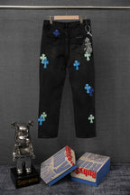 Black denim pants with scattered multicolor cross patches, front view