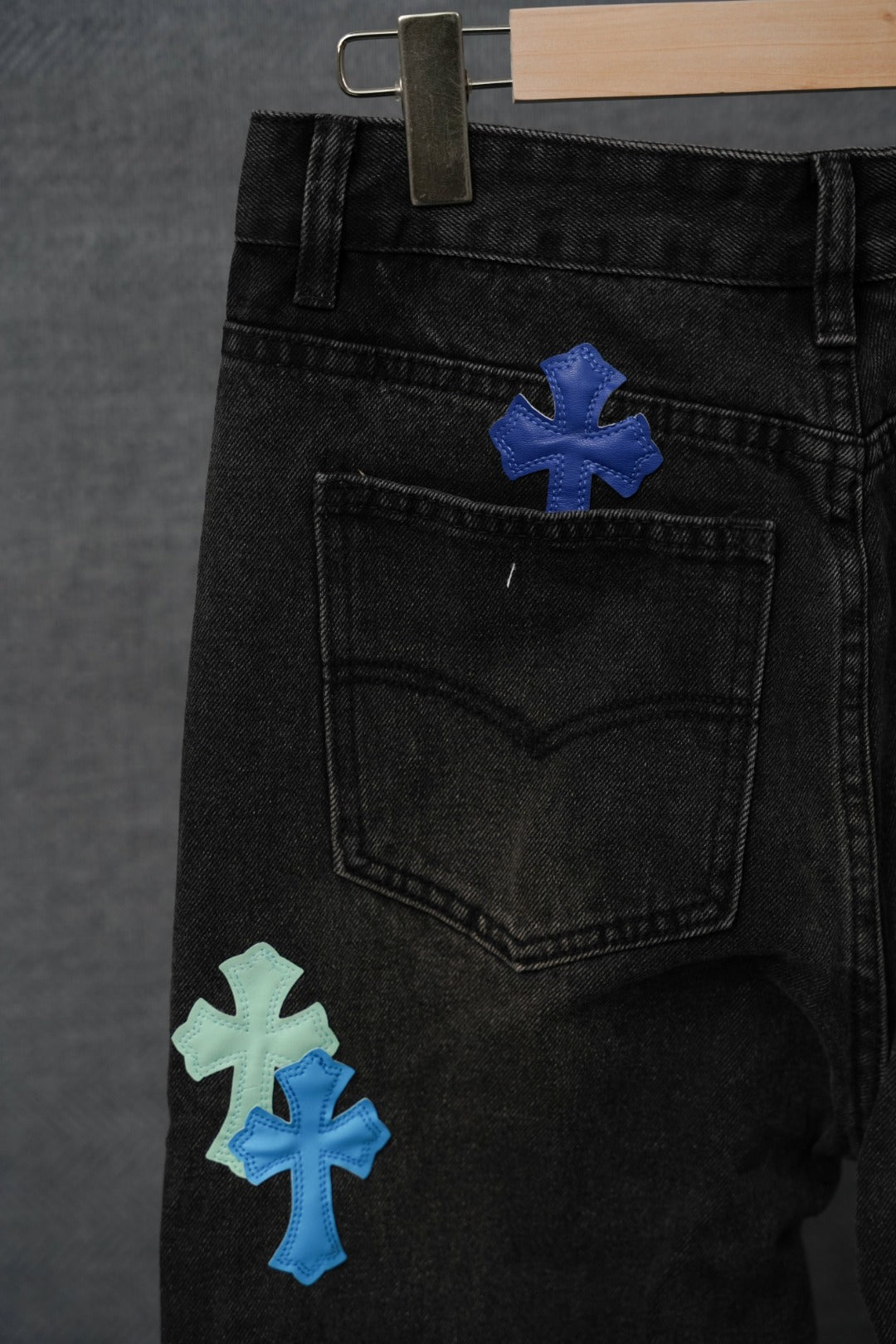 Black denim pants close-up of back pocket area with blue and mint cross patches