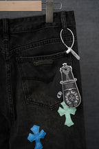 Black denim pants with front pockets, belt loops, and blue/green cross patches
