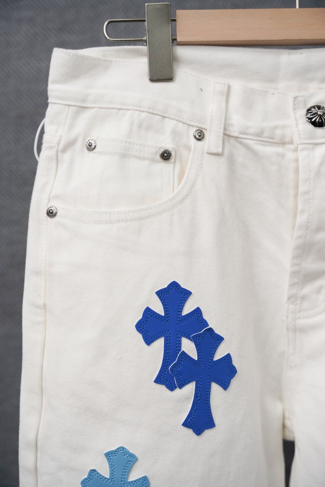 White denim pants with blue cross patch and front pocket stitch detail