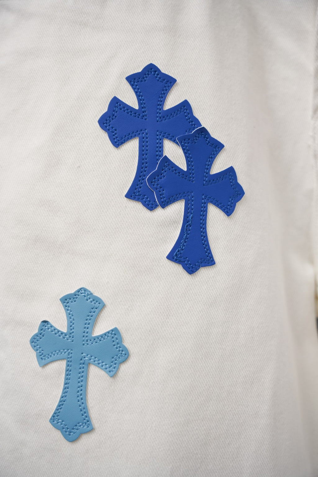 White denim fabric with large blue cross patch print details