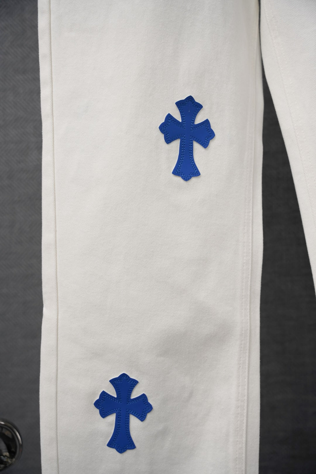 White denim pant leg with two blue cross patch prints