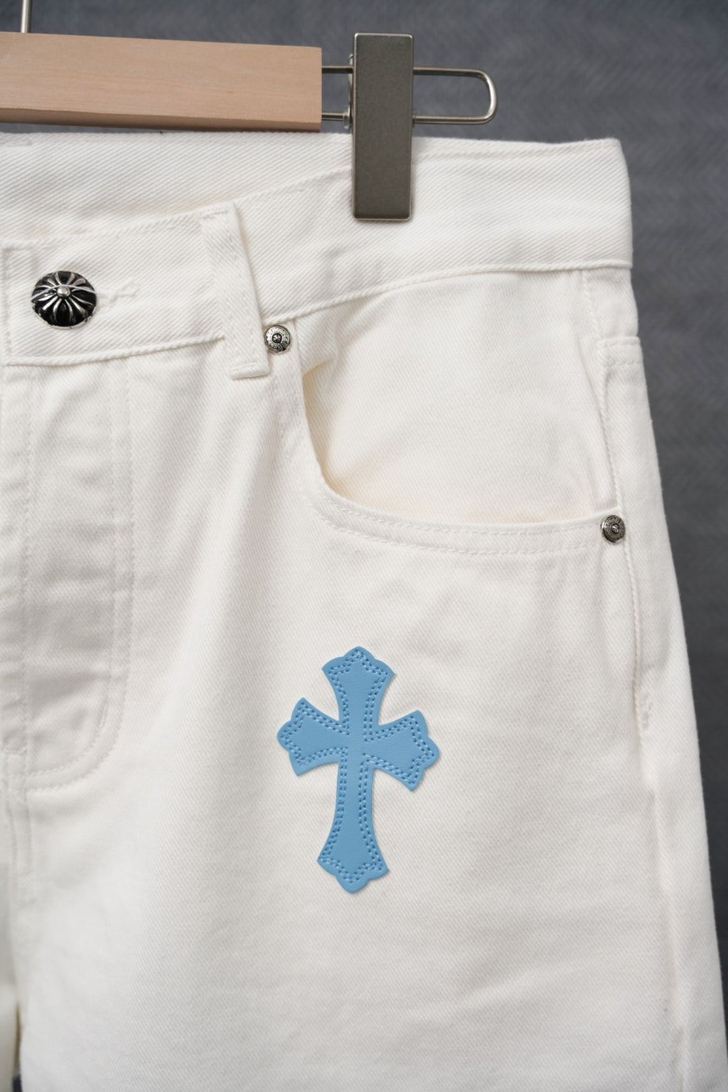 White denim pants with blue cross patch on pocket area