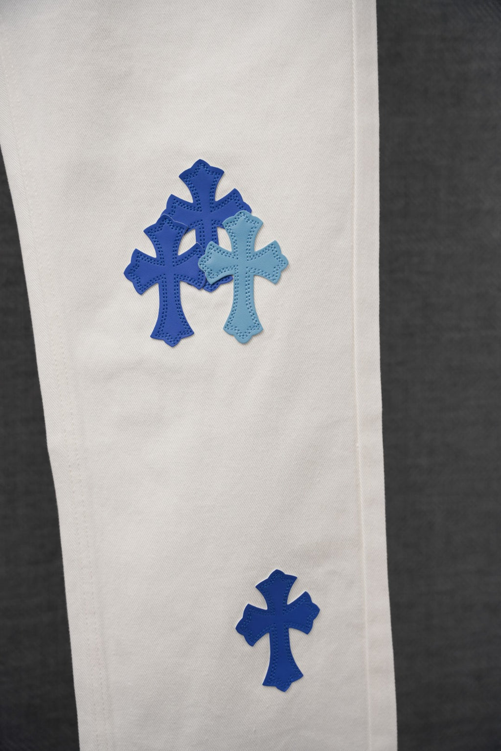 White denim pants with blue cross patches on the leg