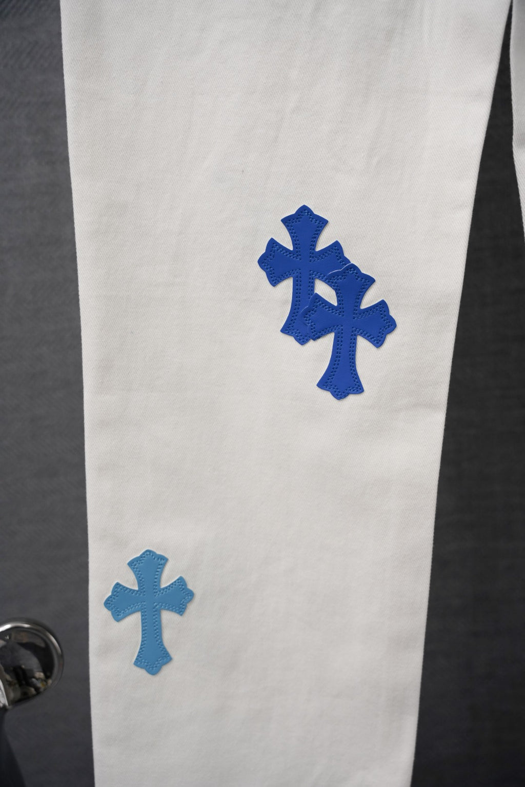 White pants with blue cross patch detail on the leg