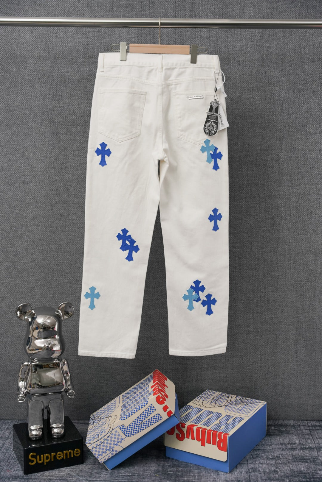 White denim pants with blue cross patch print and hanging side tag