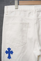 White pants with blue cross patches, pocket and waistband close-up