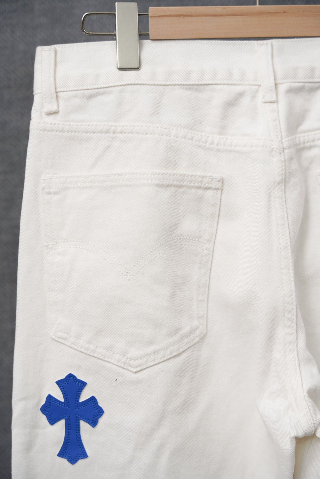 White pants with blue cross patches, pocket and waistband close-up