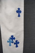 White denim pants with scattered blue cross patch prints on the leg