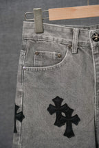 Close-up of gray denim pants pocket with black cross appliques