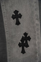 Chrome pants leg close-up, light gray denim with black cross applique