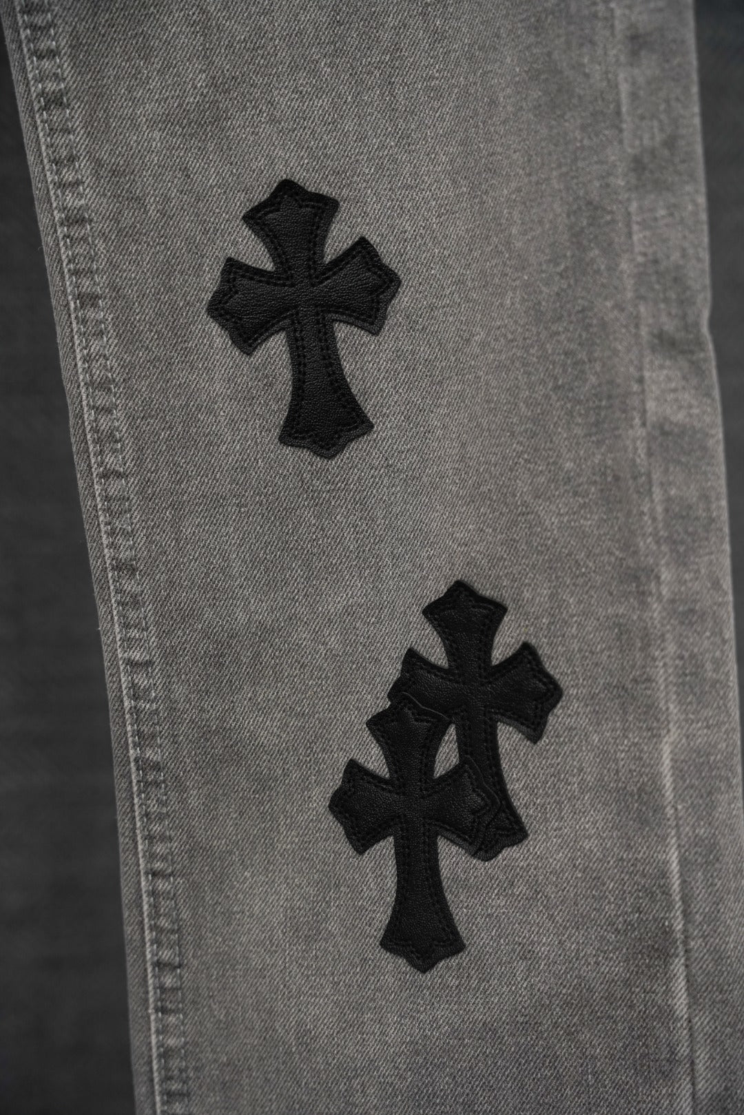 Chrome pants leg close-up, light gray denim with black cross applique