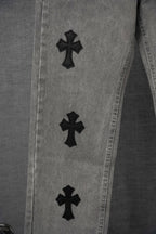 Close-up of gray denim pants legs with black cross patches