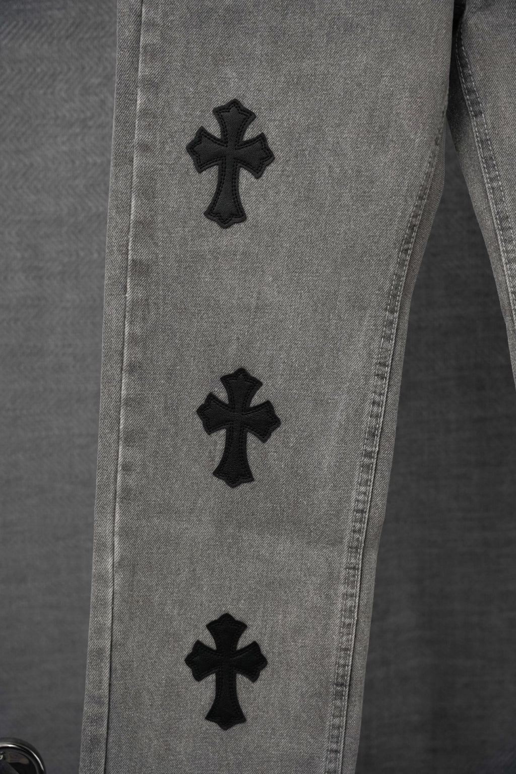 Chrome pants close-up, light gray denim with black cross patches