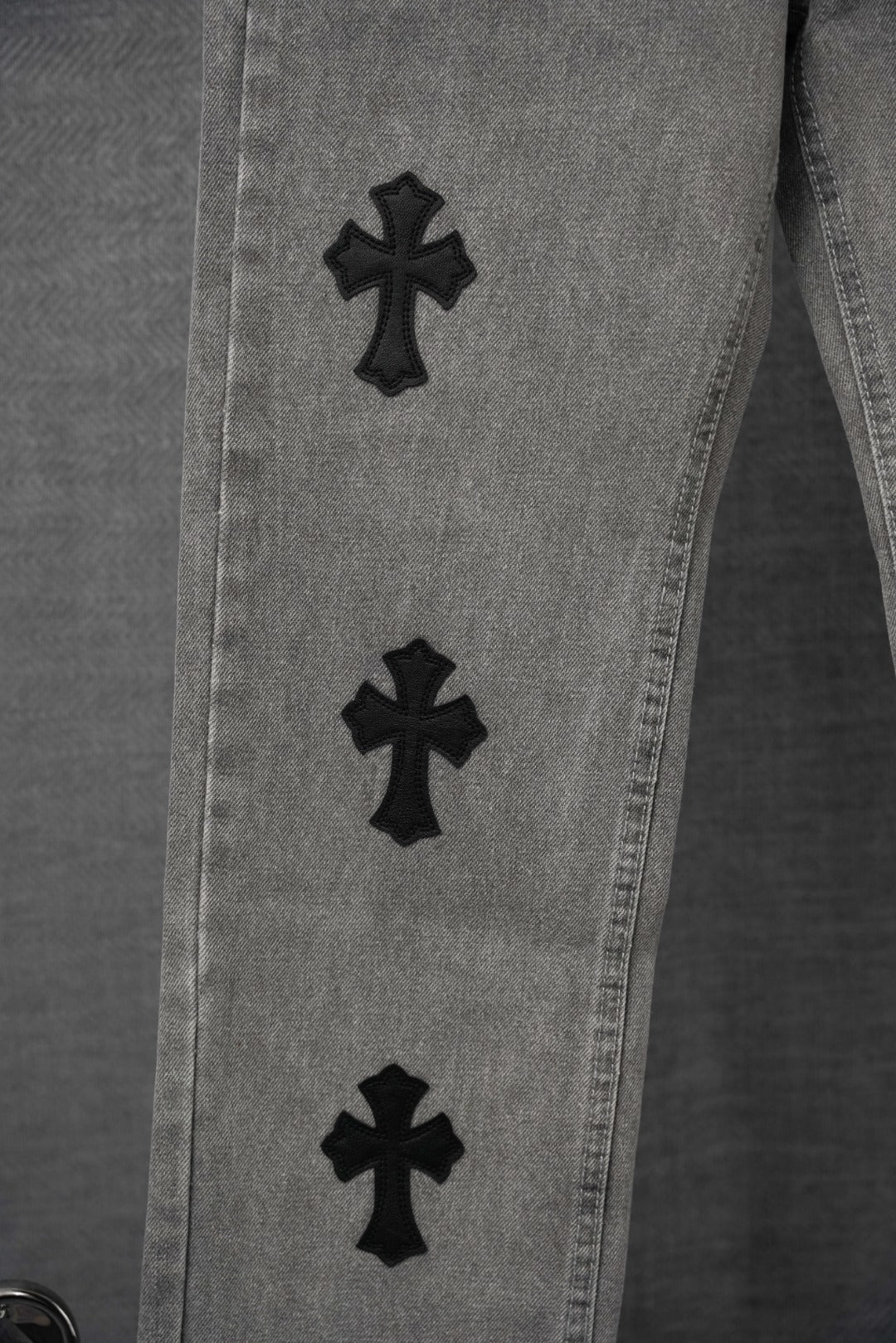 Chrome pants close-up, light gray denim with black cross patches