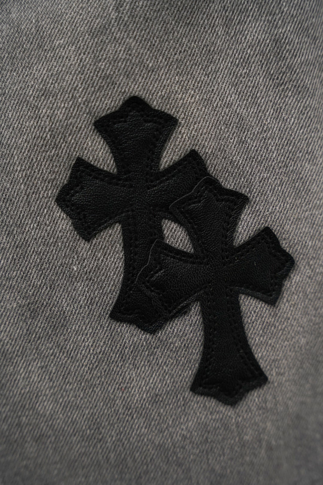 Black pants fabric detail with cross-shaped applique