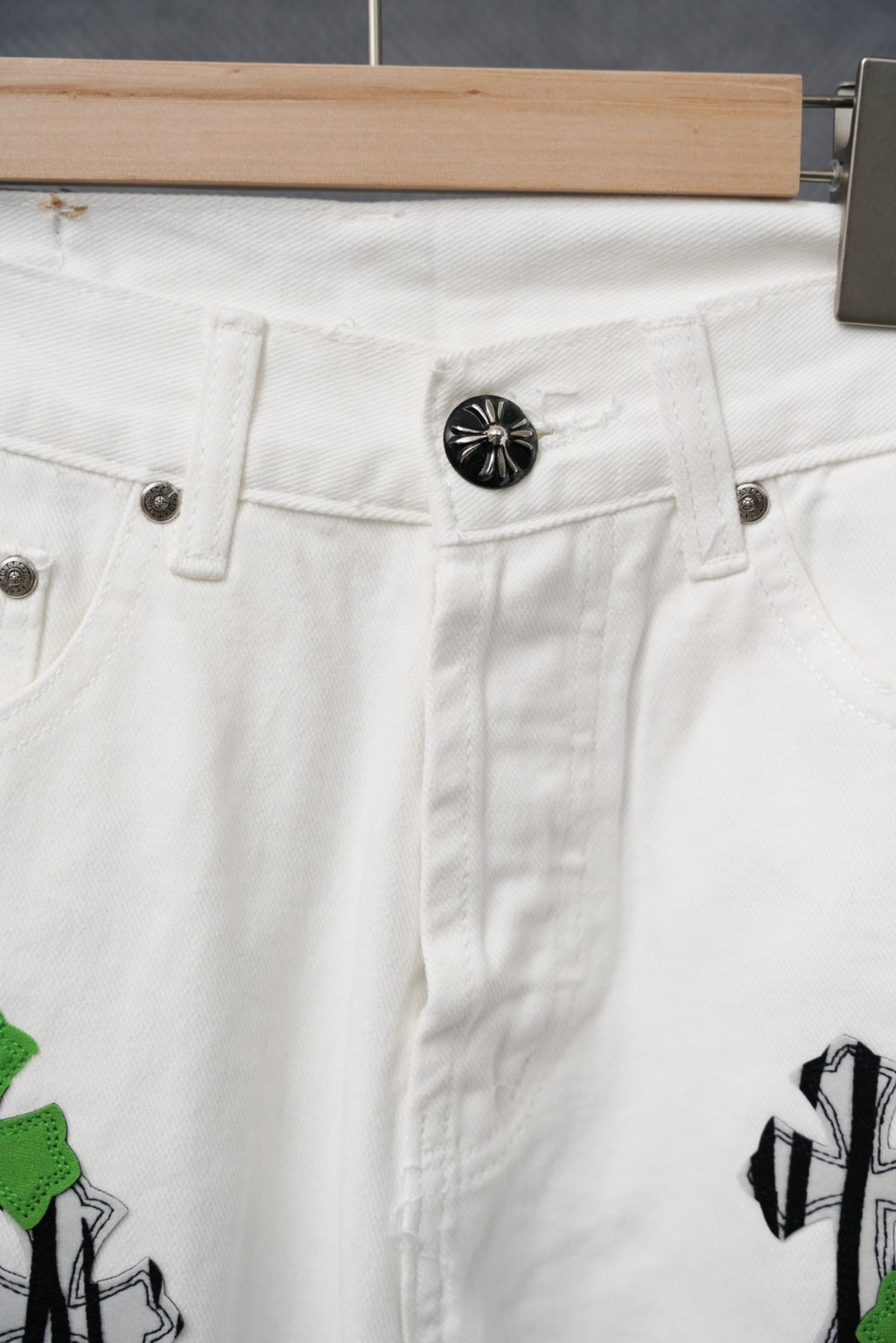 White pants waistband with button and belt loops; green and black graphic patch detail