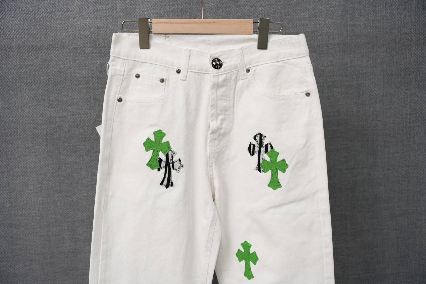 White denim pants with green cross and black striped graphic patch detail