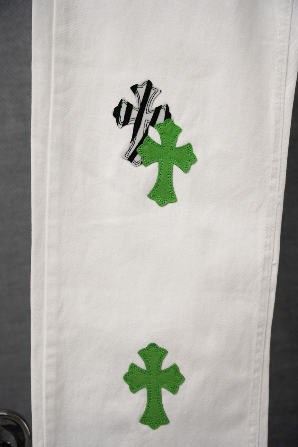 White denim with green cross-like graphic patch and black outline on leg