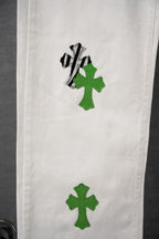 White denim with green cross-like graphic patch and black outline on leg