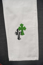 White denim leg with small green cross and black striped graphic
