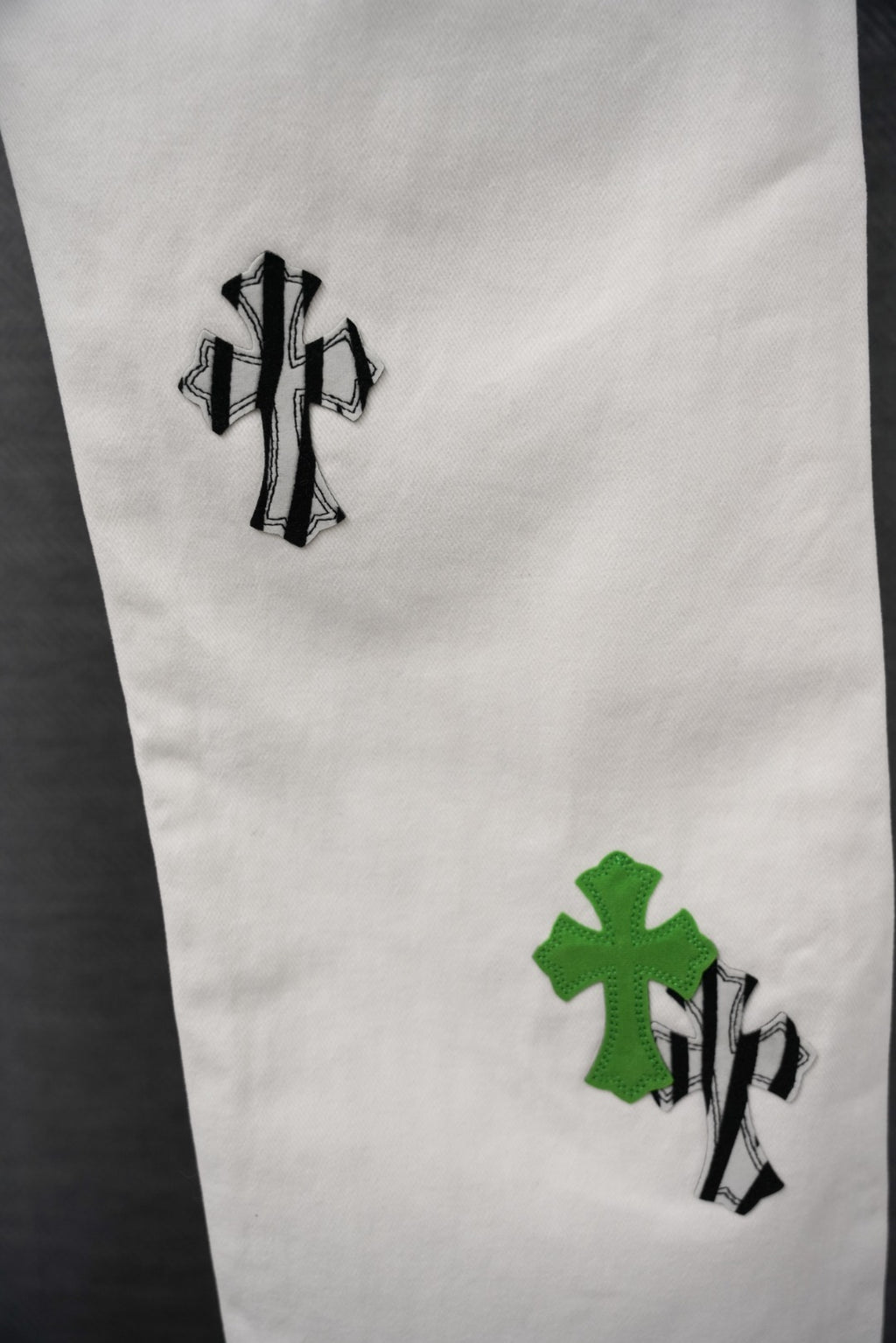 White pants leg with green cross-like graphic patches and black outlines, close-up