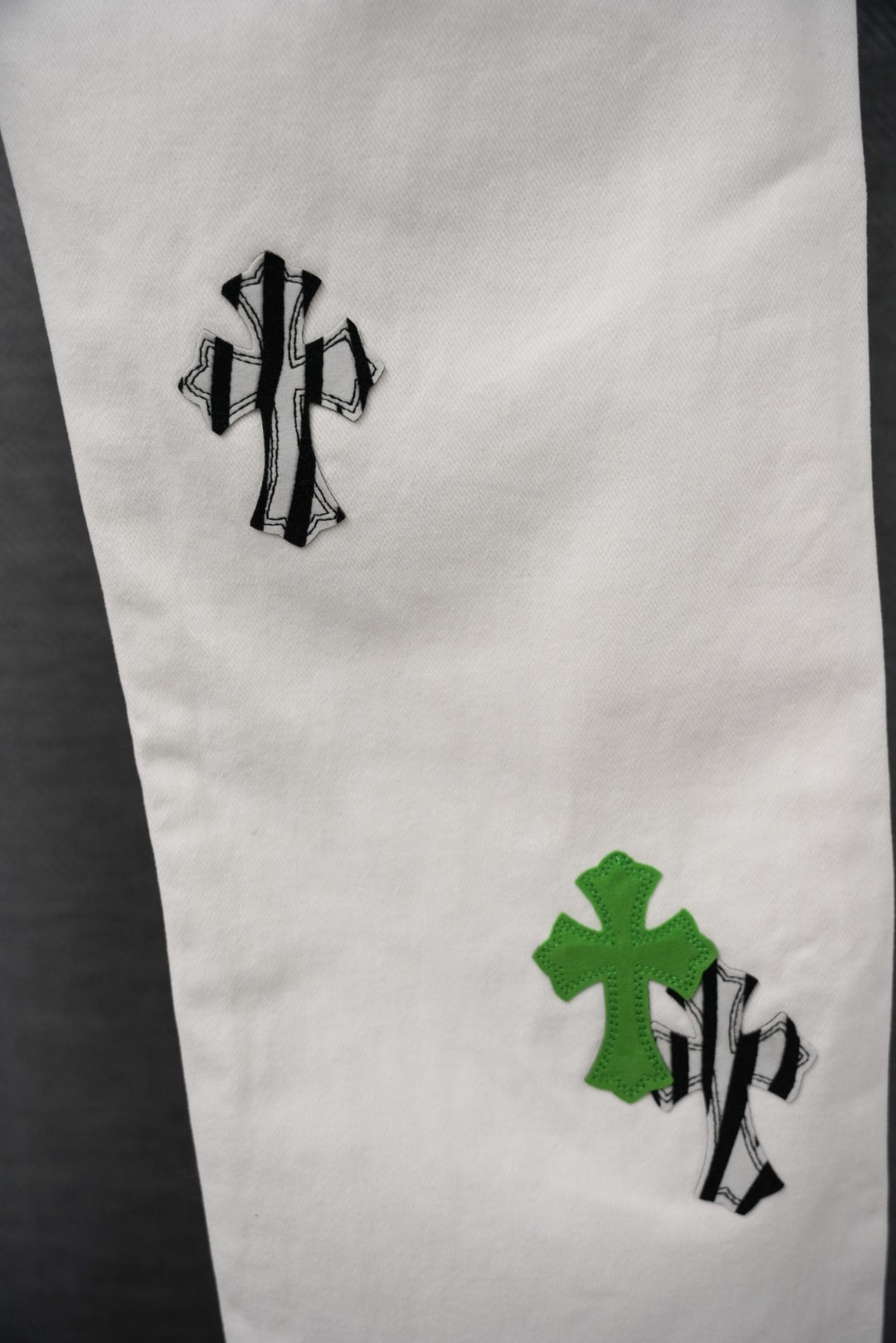 White pants leg with green cross-like graphic patches and black outlines, close-up