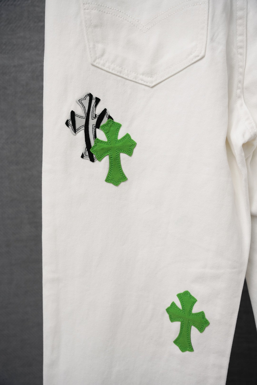 White cargo pants with green cross and black graphic patches, front pocket detail