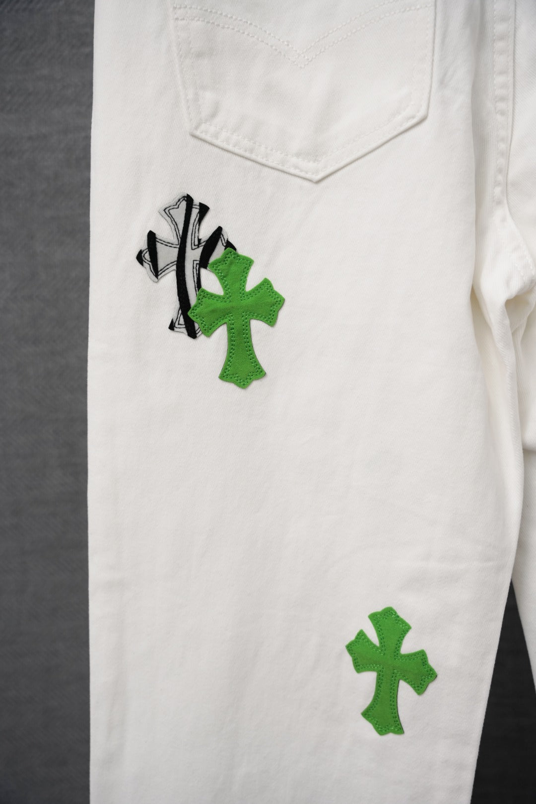 White cargo pants with green cross and black graphic patches, front pocket detail
