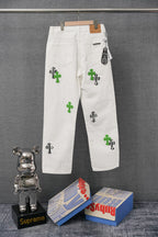 White denim pants with button waist and scattered green cross graphic accents