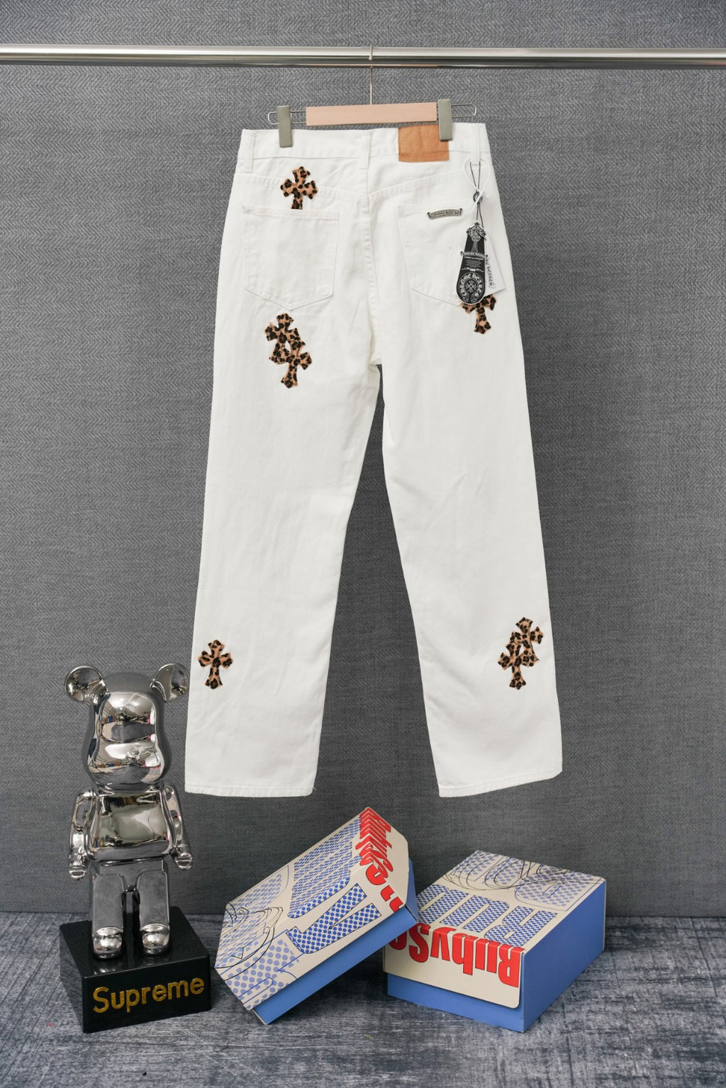 White denim pants with leopard cross patches and a small pocket logo patch