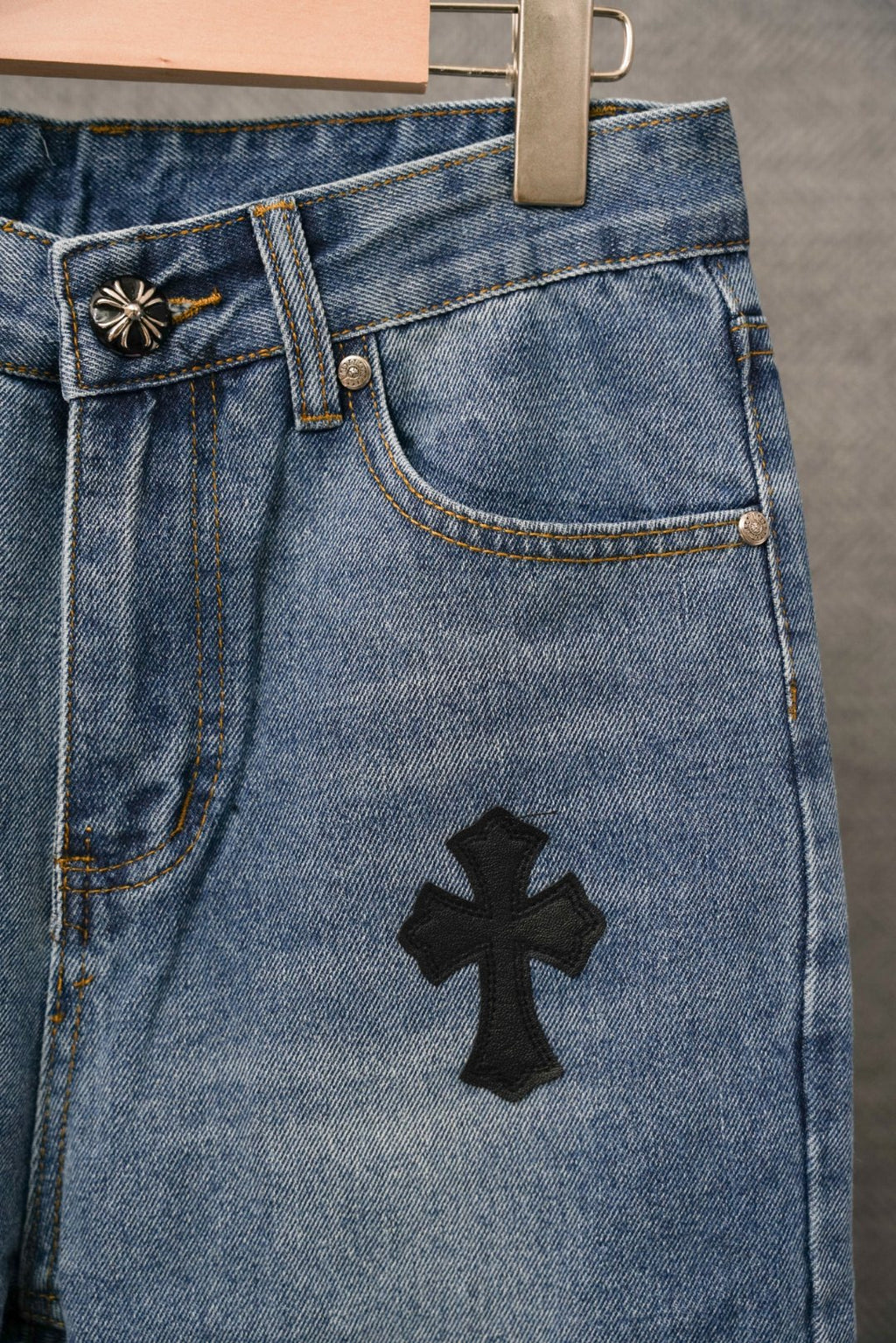 Blue denim Chrome pants with front pocket and black cross applique on leg.