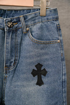 Blue denim Chrome pants with front pocket and black cross applique on leg.