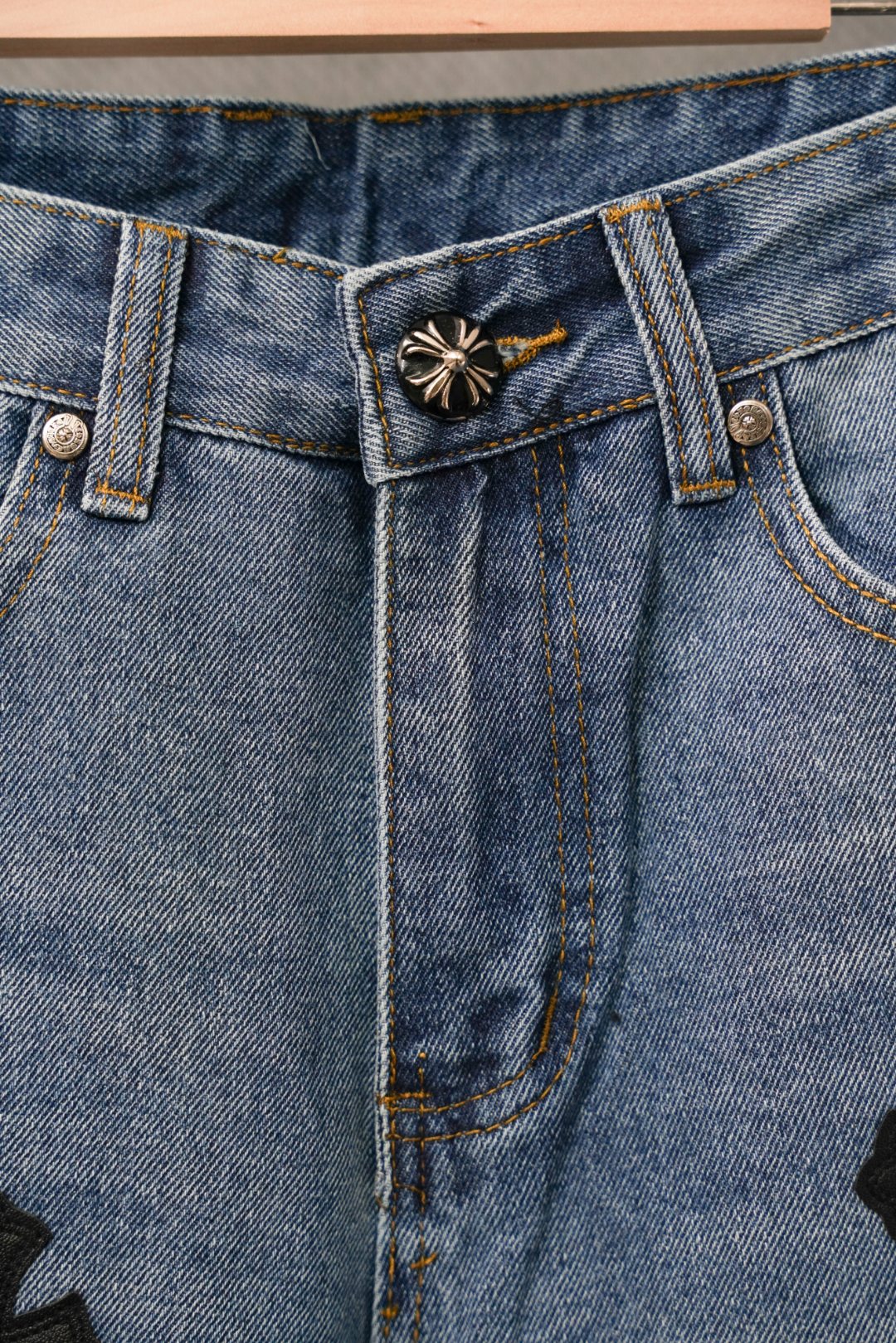 Blue denim Chrome pants front detail with belt loops and black cross patch.