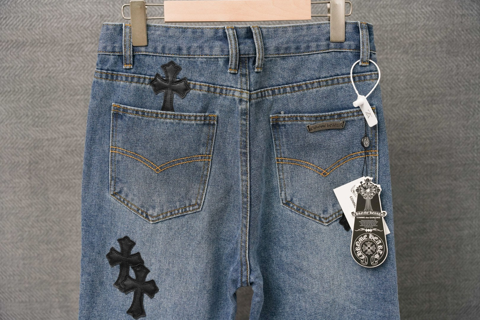 Denim pants with front pockets and black cross-style patches, drawstring waistband