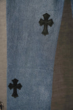 Blue denim Chrome pants leg with two black cross patches near the knee.