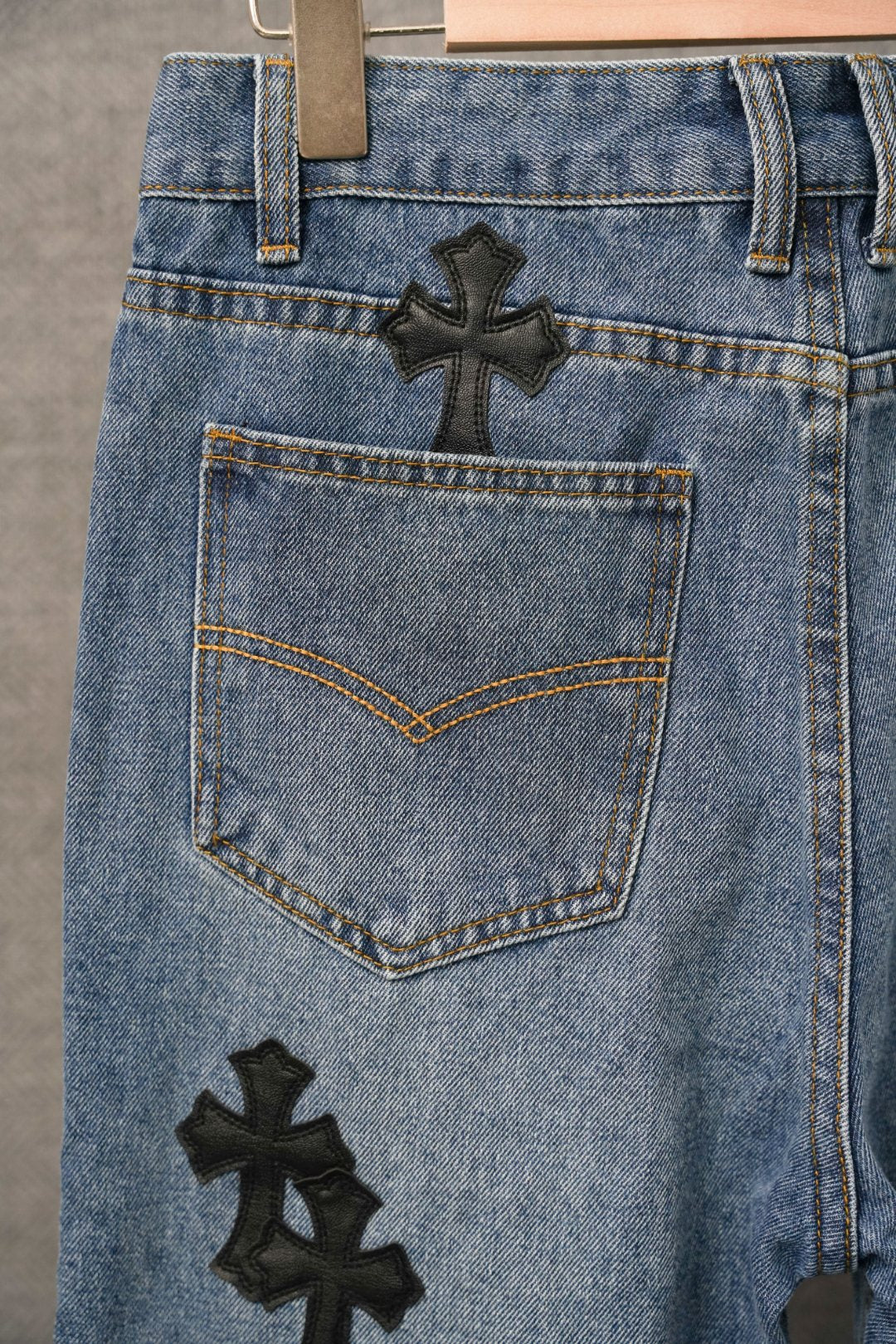 Light blue denim pants with black cross patch and large front pocket