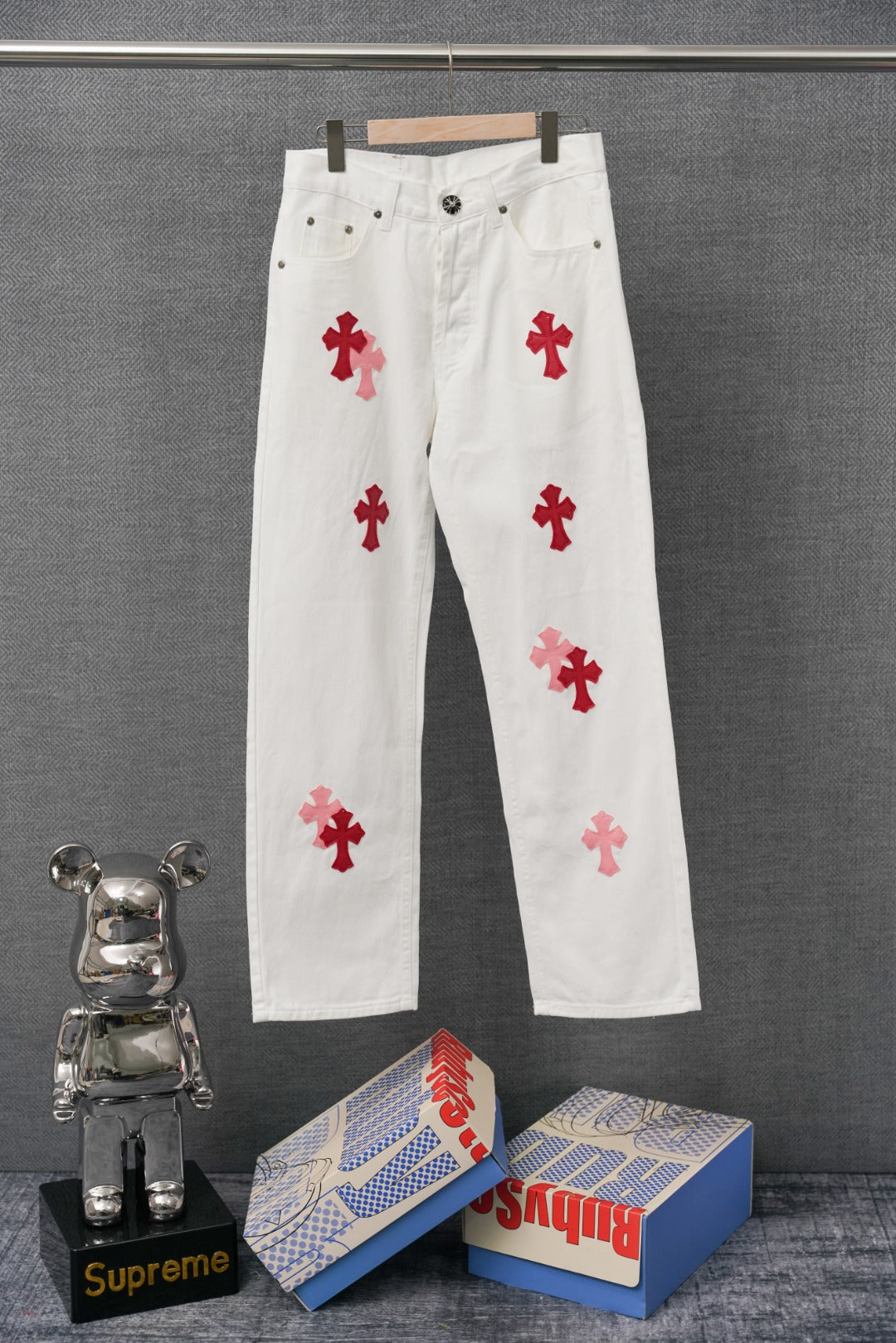 White denim pants with red cross patch graphics, front view