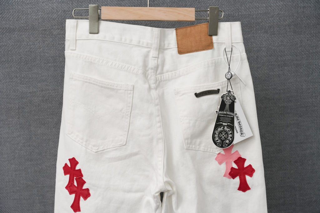 White pants with red cross applique, belt loops, and hanging brand tag