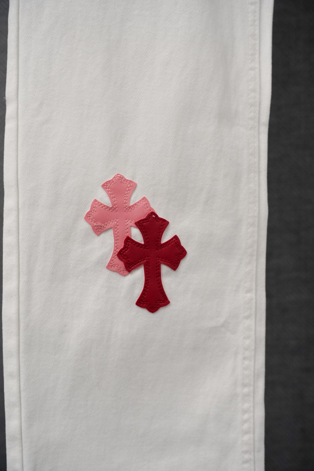 White pants with red and pink cross appliques on the side