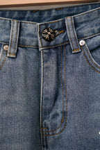 Denim pants waistband with decorative button closure and stitched detailing.