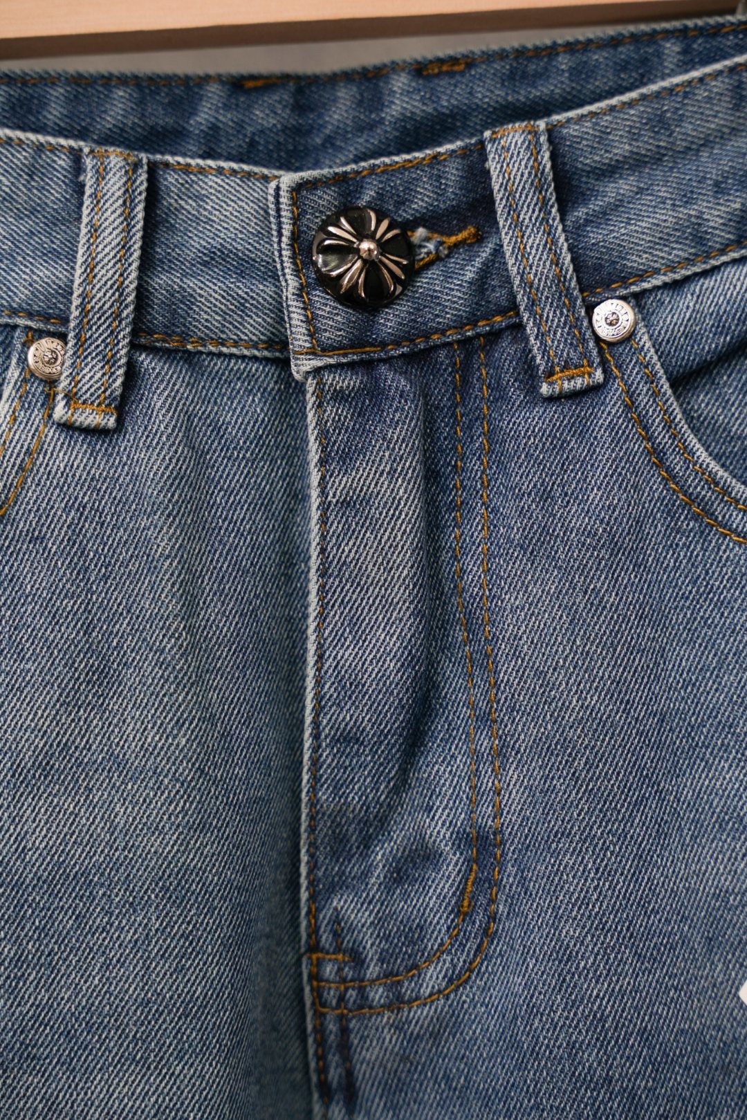 Blue denim pants close-up of waistband with decorative button and stitched pocket