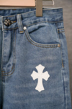 Blue denim pants close-up of side seam and white cross patch on front