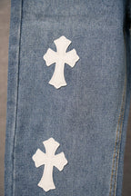 Blue denim pants with two white cross patches near the lower leg.