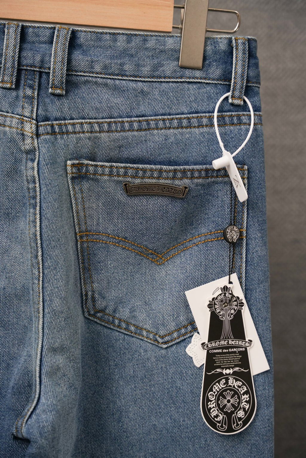 Blue denim pants with belt loops and label detail over a white cross pocket patch