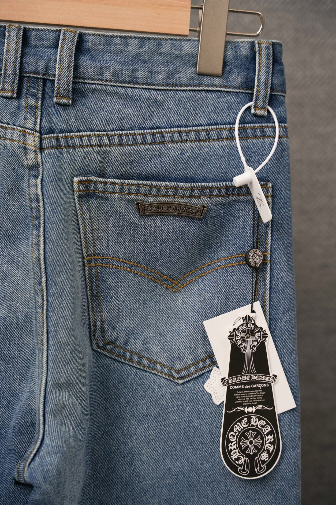 Blue denim pants with belt loops and label detail over a white cross pocket patch